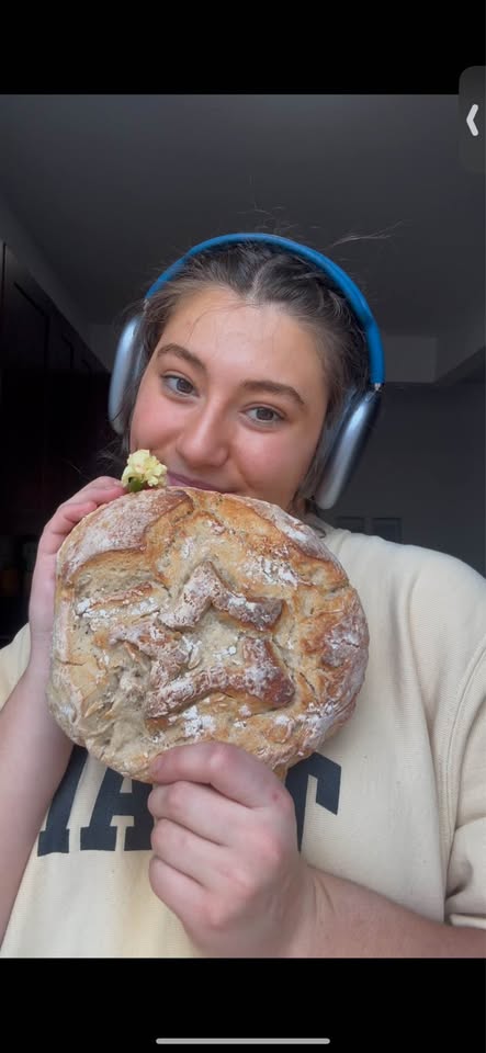Persephone holding a sourdough loaf with a star scoring design